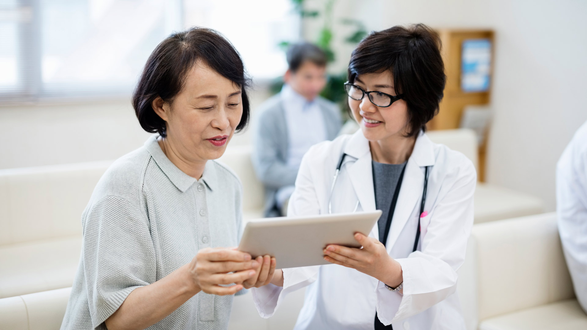 female Doctor showing digital tablet to patient in hospital, ekas, healthcare research, japan